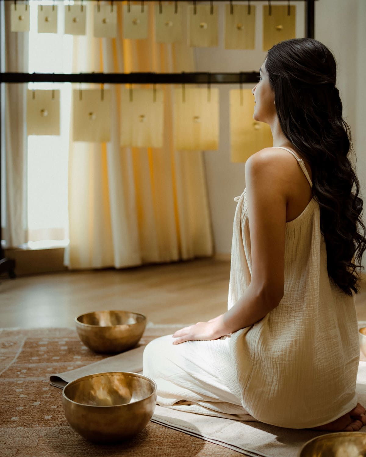 Woman meditating with singing bowls during a sound healing therapy at Dhun