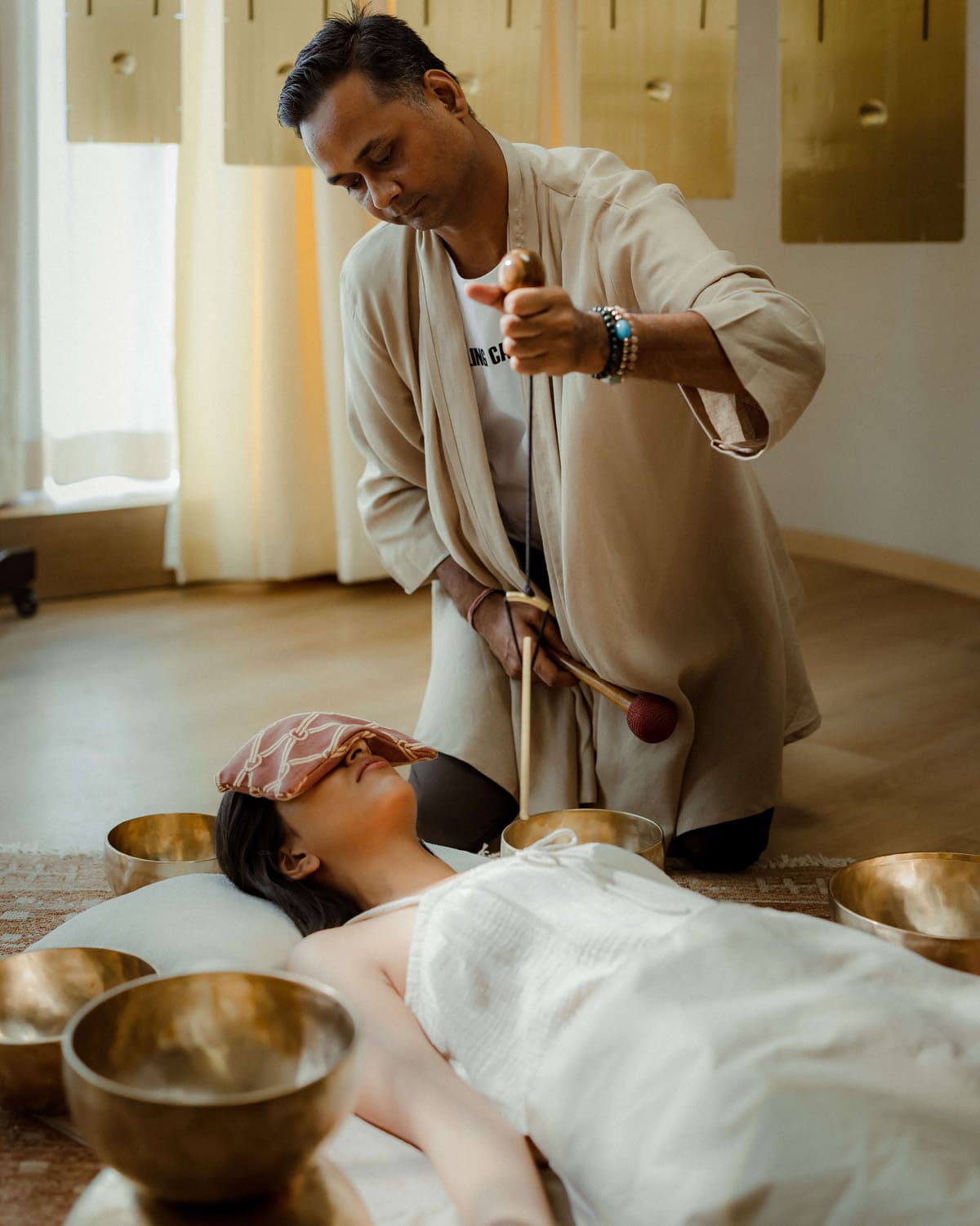 Woman receiving sound healing therapy with singing bowls at Dhun.